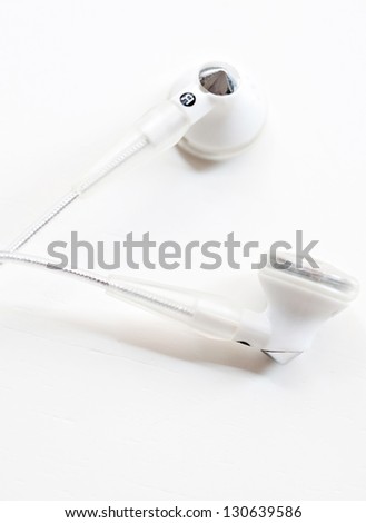 Close up detail view of a pair of musical earphones laying together on a white background.