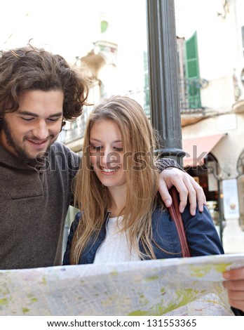 Portrait of a young tourist couple visiting a destination city and reading a street map while on vacation in Europe.