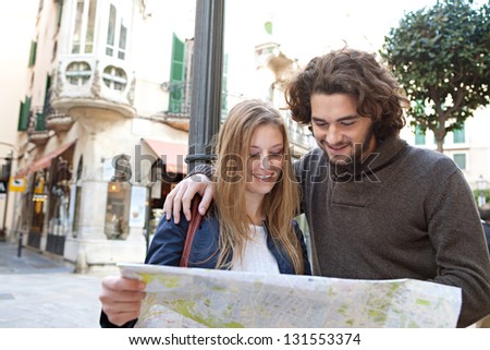 Portrait of a young tourist couple visiting a destination city and reading a street map while on vacation in Europe.