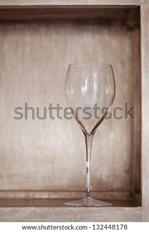 Full view of a red wine glass standing on a traditional wooden shelf in a kitchen at home.