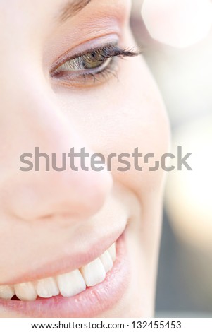 Over head close up beauty portrait of a young caucasian healthy woman face and eye looking down with long eyelashes and sparkling lights in the background.