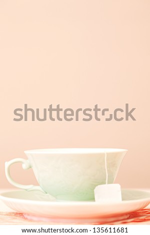 Close up profile view of a decorative cup of tea with a tea bag blank tag hanging against a spacious wall in a home.