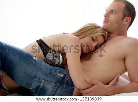Close up view of a sexy couple laying down in bed, relaxing and hugging in intimacy.