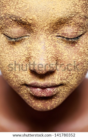 Close up beauty portrait of a young african american black girl face with yellow cosmetic powder covering her face, with her eyes closed.