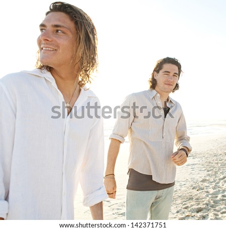 Two young men friends hanging around on vacation together at sunset while on a beach having fun during the summer.