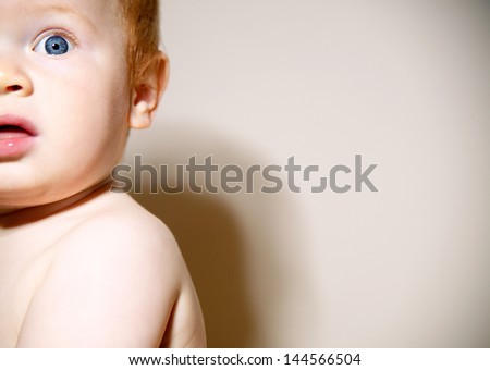 Close up portrait of a baby boy half face with red hair and blue eyes looking up against a white background with a retro style.