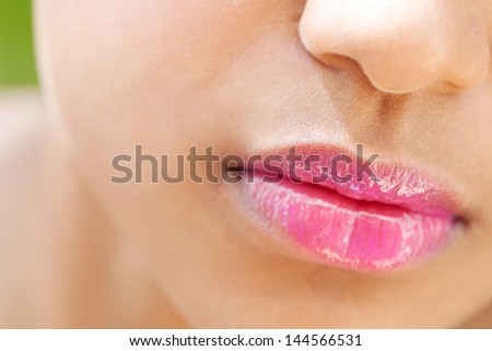 Close up detail view of a beautiful young woman\'s mouth with perfect lips wearing glossy pink lipstick outdoors.