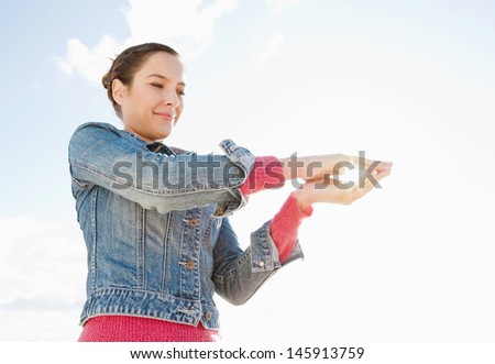Attractive young woman holding the sun between her hands against an intense blue sky, smiling and protecting the environment and natural resources.