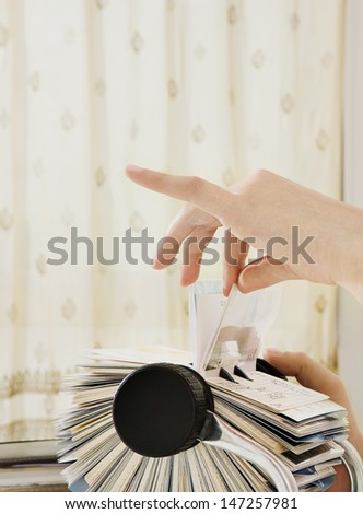 Close up profile view of a young business woman hand on her office desk carefully selecting a business card contact details from her roller deck database, interior.
