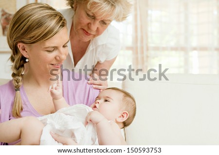 Close Up Portrait Of Three Generations Of Women Being Close, Grandmother, Mother And Baby Daughter At Home, Being Calm And Relaxing Together Around Each Other.