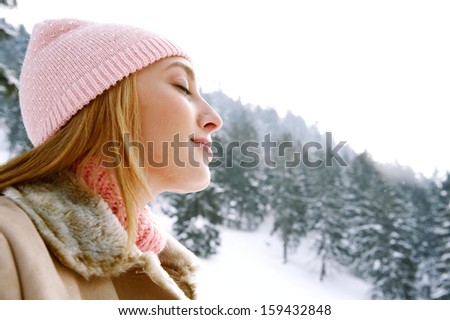 Close Up Side Beauty Portrait Of A Young And Attractive Woman Breathing Fresh Air In The Snow Mountains With Her Eyes Closed, Feeling Healthy And Dreamy During A Cold Winter Day Outdoors.