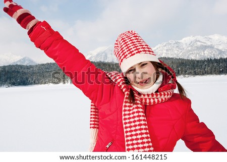 Close up portrait of a beautiful young woman on vacation in the snow mountains running and playing with her arms stretched, feeling free and joyful during a sunny winter day, outdoors.