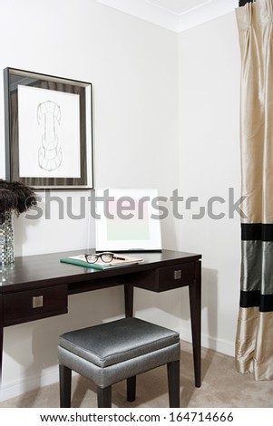 Still life of a bedroom corner with curtains and a writing desk in a luxury hotel room with reading glasses and a pen. Stylish home interior with no people.