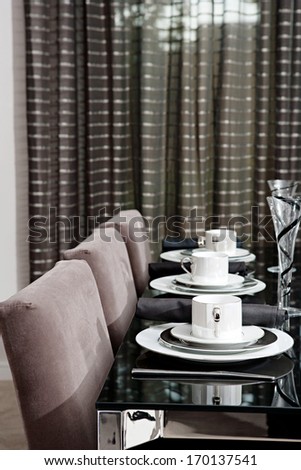 Still life detail view of a luxury home festive diner table set for evening guests. Designer home interior with elegant furniture and tableware. Hotel interior.