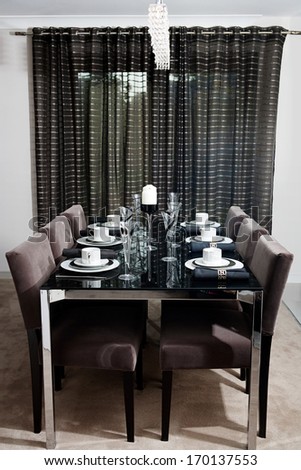 Still life detail view of a luxury home festive diner table set for six evening guests. Designer home interior with elegant furniture and tableware. Hotel interior.