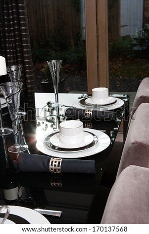 Still life detail view of a luxury home festive diner table set for evening guests. Designer home interior with elegant furniture and tableware. Hotel interior.