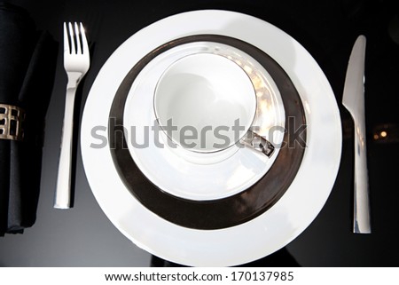 Over head still life view of a luxury home festive diner table set with cutlery, plates and cups for evening guests. Designer home interior with elegant furniture and tableware. Hotel interior.