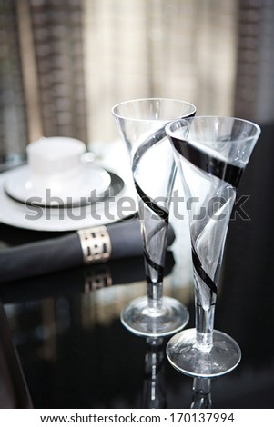 Still life detail view of a luxury home festive diner table set with champagne glasses for two evening guests. Designer home interior with elegant furniture and tableware. Hotel interior.