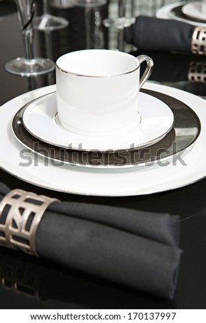 Still life detail view of a luxury home festive diner table set with glasses, plates and cups for evening guests. Designer home interior with elegant furniture and tableware. Hotel interior.