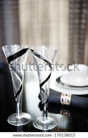 Still life detail view of a luxury home festive diner table set with champagne glasses for two evening guests. Designer home interior with elegant furniture and tableware. Hotel interior.