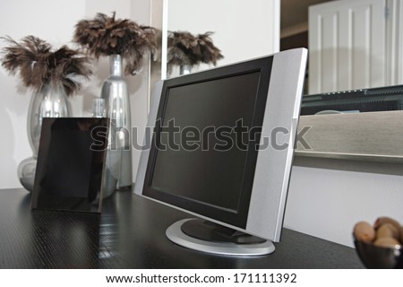 Still life view of high technology in a living room with a flat screen tv and a digital photo frame on a wooden table in a luxury home. Elegant hotel bedroom interior with technology.