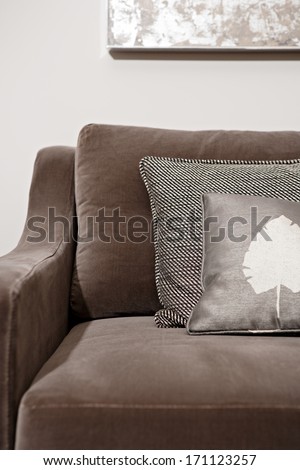 Still life close up view of an elegant brown sofa in a luxury home living room with different natural fabrics cushions and textures. Hotel interior suite detail.