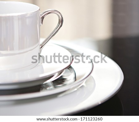 Close Up Still Life Detail View Of Half A Serving Set Of Plates And Cup For One On A Luxury Reflective Diner Table In A Quality Home With Smart Curtains. Home Interior Detail View.