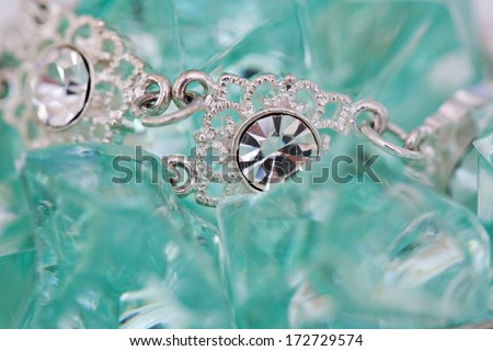 Close up detail view of a fine quality luxurious diamond necklace on a green turquoise minerals stone bed background. Diamond stones on white gold bracelet jewel and fashion accessory.