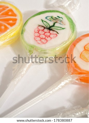 Still life detail view of various candy sweets with different fruit flavors wrapped in clear plastic laying together on a white background. Colorful sweet tooth sugar sticks.