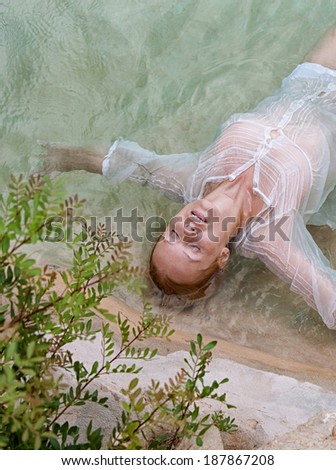 Over head beauty portrait of a young woman lying and relaxing in the clear blue waters of a health spa natural swimming pool with her eyes shut, enjoying a summer holiday, outdoors healthy lifestyle.