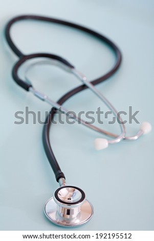 Over head close up detail still life view of a doctor stethoscope laying on a plain blue background in a hospital table, interior. Health and medical equipment and insurance icon with no people.