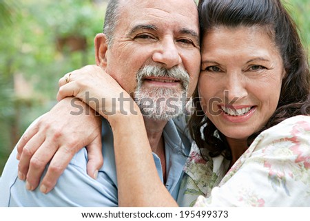 Close up portrait of a healthy and attractive senior couple relaxing on holiday, hugging each other, being loving and affectionate. Mature people enjoying romance and retirement, outdoors lifestyle.