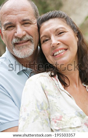 Close up portrait of a healthy and attractive senior couple relaxing on holiday, leaning on each other and being loving and close. Mature people enjoying romance and retirement, outdoors lifestyle.