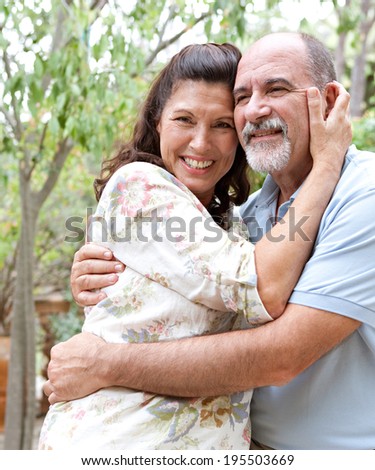 Close up portrait of healthy and attractive senior couple relaxing on holiday, hugging each other and being loving and affectionate. Mature people enjoying romance and retirement, outdoors lifestyle.