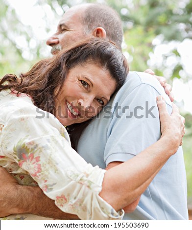 Close up portrait of healthy and attractive senior couple relaxing on holiday, hugging each other and being loving and affectionate. Mature people enjoying romance and retirement, outdoors lifestyle.