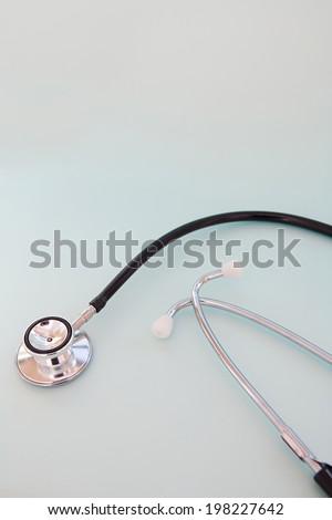 Still life close up detail view of a doctor stethoscope laying on a plain blue background, surgery interior. Medical and hospital equipment for heart and respiratory conditions.