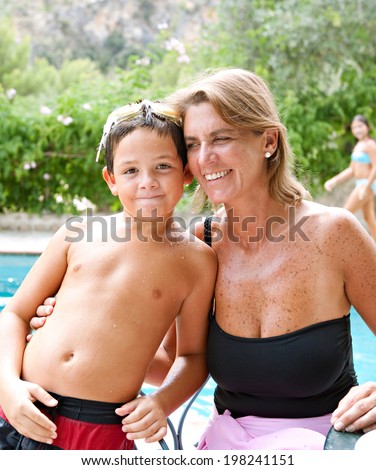 Close up portrait of a joyful mother and son enjoying a summer day together in a holiday home garden and swimming pool, having fun and being active. Vacation and relaxing family lifestyle, outdoors.