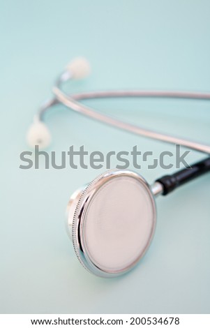 Close up still life view of a doctor stethoscope laying isolated on a blue background. Medicine and medical equipment. Iconic objects, interior.