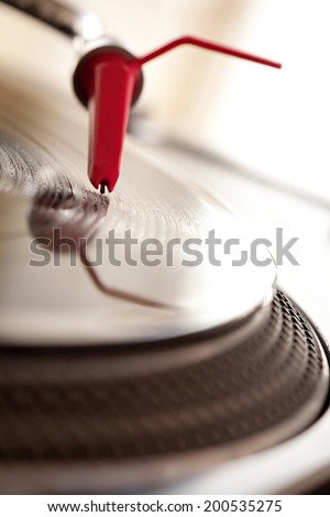 Macro close up detail view of a record player with a red needle touching the groove of a vinyl album playing music, interior. Still life professional musical equipment objects.