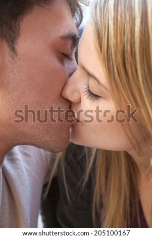 Close up portrait of a beautiful young couple in love, innocently kissing with their eyes shut. Relationships feelings and emotions, outdoors.