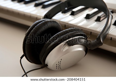 Still life close up of two electronic music and sound devices laying together on a white desk in a recording studio, interior. Detail view of a pair of headphones and a keyboard, technology.