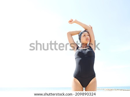 Spacious portrait of a healthy african american teenager woman swimmer standing and stretching against a sunny blue sky preparing for training. Confident teenager, sport lifestyle outdoors.