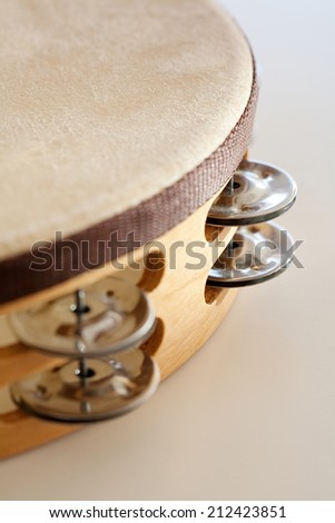 Close up still life detail of a wooden tambourine percussion instrument isolated on a white background. Music and creative sound objects, interior.