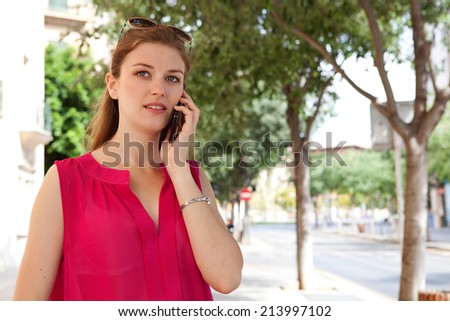 Portrait of a beautiful young business woman using a smartphone in the city to make a call and have a conversation, walking in a classic street. Professional woman using technology outdoors.