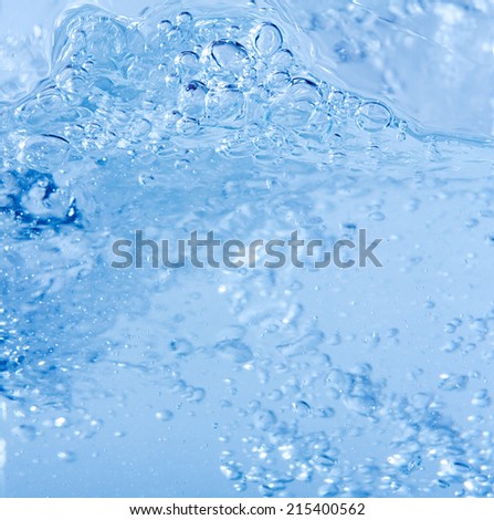 Close up macro background detail of blue water liquid in motion, moving and shining with air bubbles. Still life of water texture and color.