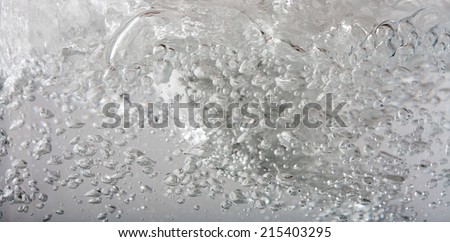 Close up macro background detail of silver gray metallic mercury water liquid in motion, moving and shining with air bubbles. Still life of water texture and detail.