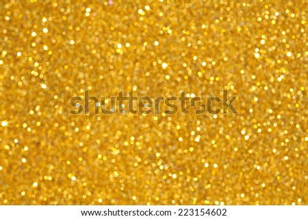 Abstract detail background of a vivid bright gold glitter shining and sparkling with lights. Full frame blurry golden yellow noise color backdrop element.