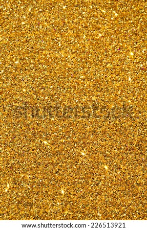 Abstract detail background of a vivid bright gold glitter shining and sparkling with texture. Galaxies and stars, full frame yellow noise color backdrop element. Vertical view.