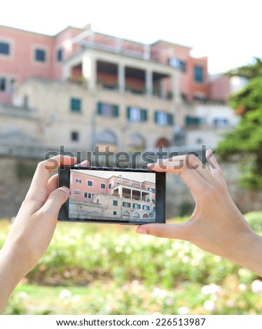 Close up of a young woman hands holding a modern smart digital phone device taking pictures of characterful architecture visiting a destination city on holiday. Vacation technology lifestyle.