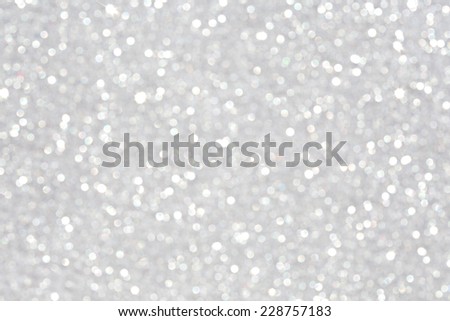 Close up detail view of silver glitter background shining and reflecting light with stars in a soft blurred view. Glitter texture. Party, celebration, abstract and festive background textures.